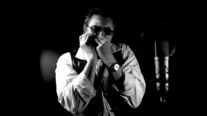 Black & white photo of Graham Pike playing on harmonica