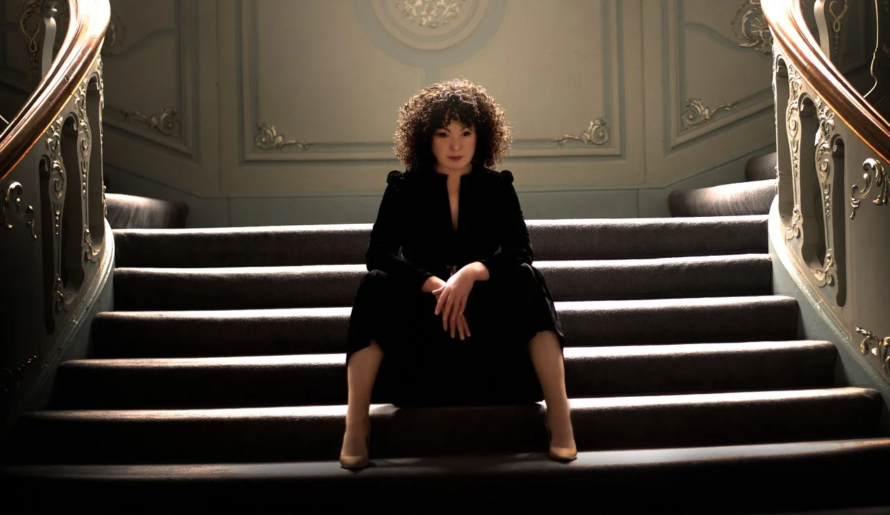 Singer Zoe Francis sitting on stairs in black dress