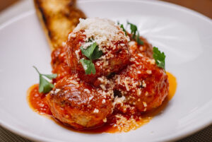 top view of meatballs plate garnished with tomato sauce grated parmesan and parsley
