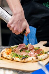 Parmigiana Pizza – a delicious Italian pizza topped with tomato, fior di latte mozzarella, Parma ham, fresh rocket, and flaked Parmigiano Reggiano, a flavourful choice from Sicily Restaurant’s menu.