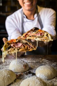 Panuozzo – a freshly baked Italian sandwich made with homemade pizza dough, available daily from 12-4 PM at Sicily Restaurant for a perfect lunchtime bite.
