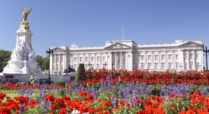 View of Buckingham Palace from the gardens during the Summer Opening 2025, with green lawns and visitors enjoying the sunshine.